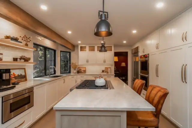 Oak and Ivory kitchen remodel in Sammamish with oak beams and open shelves, a pale stone island and paneled cabinetry
