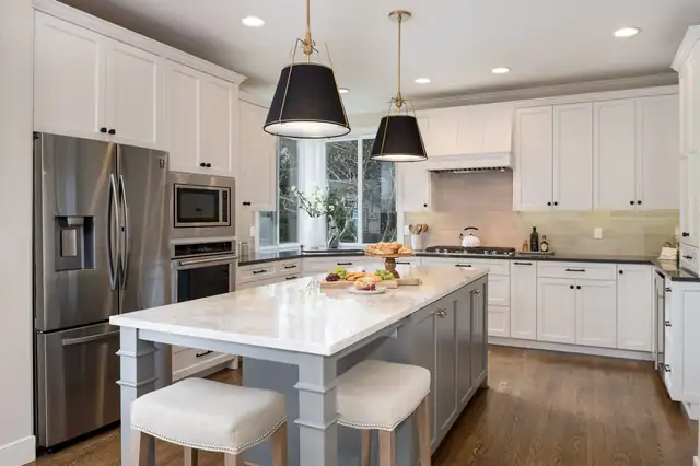 Classic Elegance kitchen remodel in Redmond with white cabinets, a gray island, black drum pendants and stainless appliances