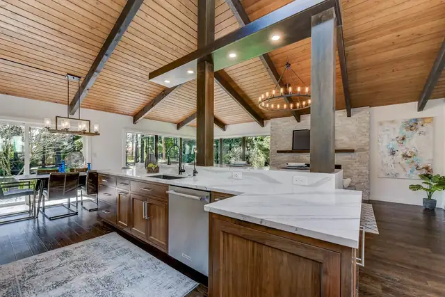 Modern Craftsman kitchen on the Eastside with a vaulted wood ceiling, exposed beams and a veined quartz island
