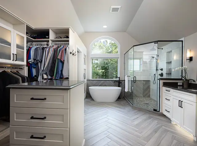 Primary suite with a walk-in closet island, a freestanding tub, a glass shower and herringbone tile floors