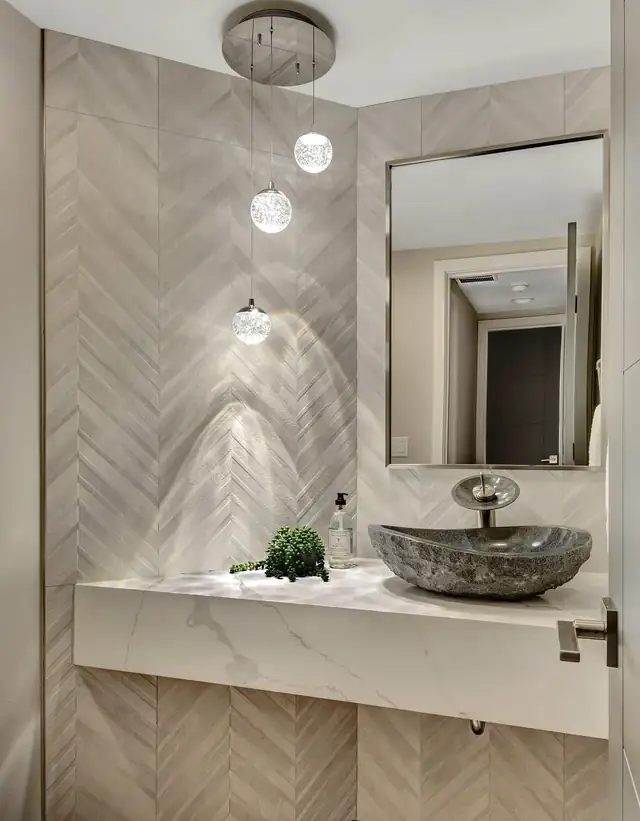 Powder room with a floating quartz vanity, a stone vessel sink, herringbone wall tile and glass globe pendants
